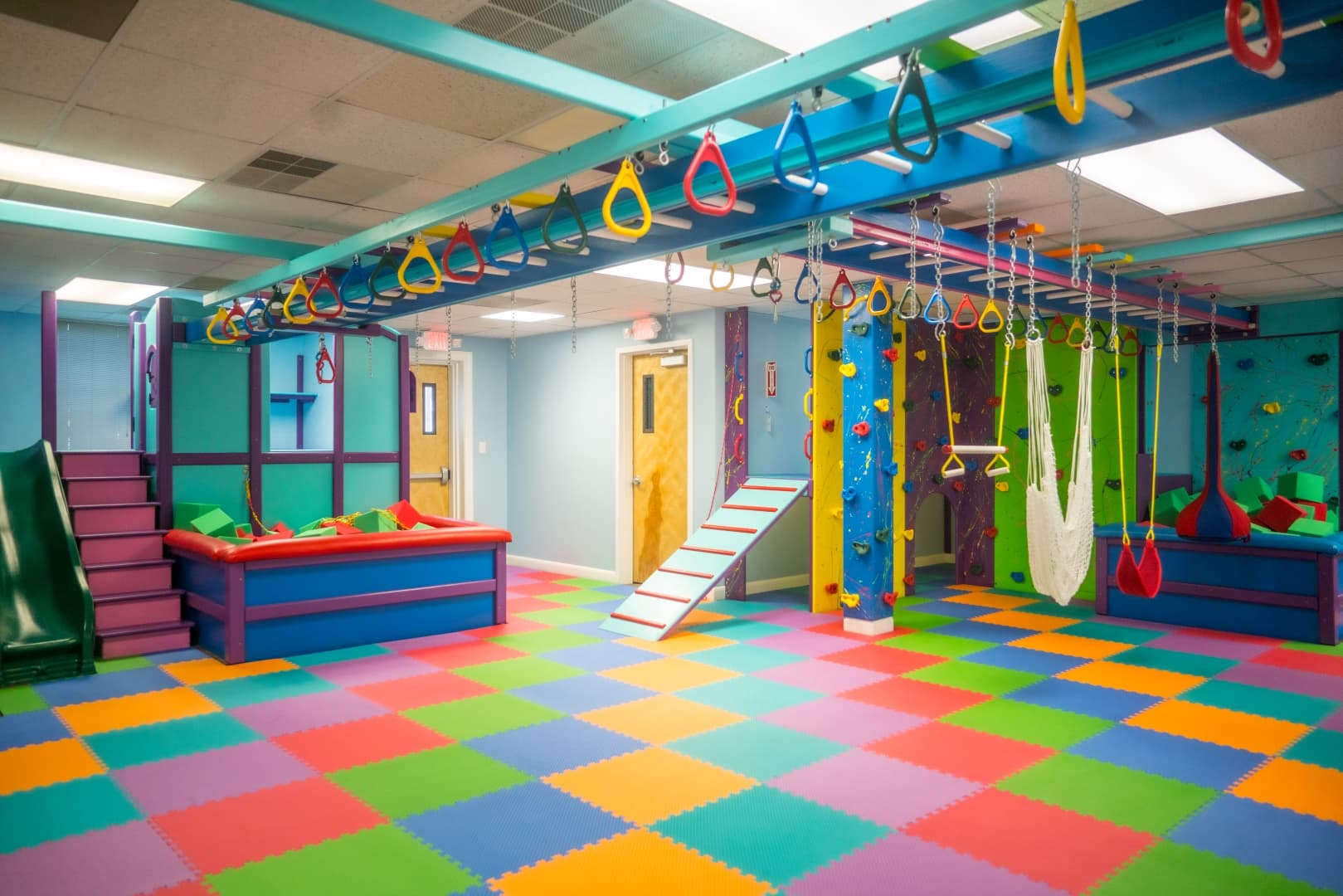 Large Delaware gym with overhead ring track, climbing walls, and rainbow floor mats
