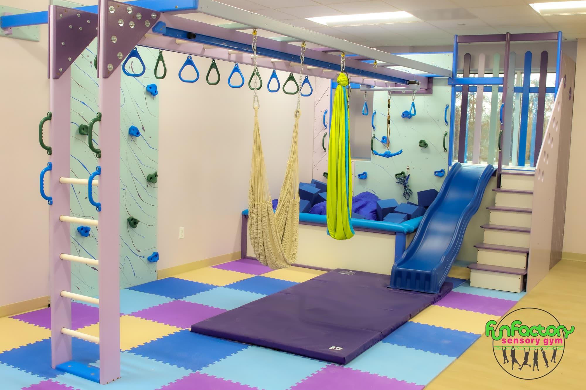 Professional clinic sensory gym with purple slide and climbing wall