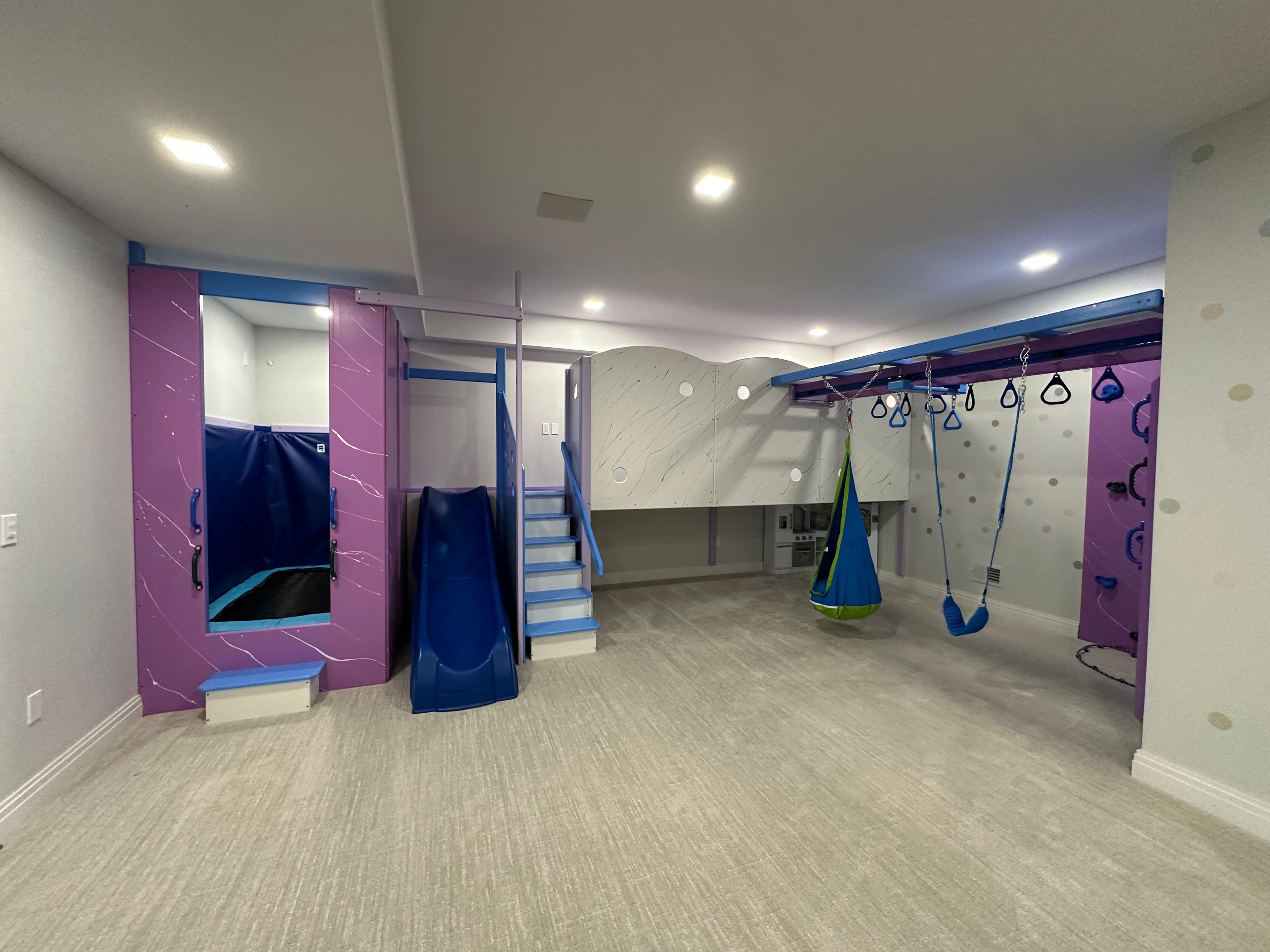 Completed custom sensory gym with slide, swings, and climbing wall